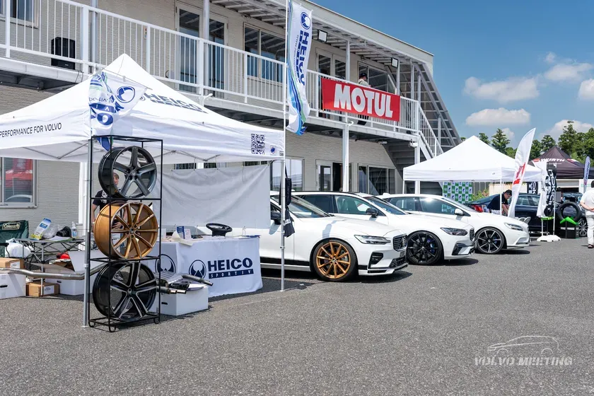 白のボルボ車が並んだイベントの様子。HEICO SPORTSのテントがあり、ホイールが展示されている。