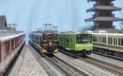 鉄道模型の写真。複数の電車が線路上を走っており、背景には五重塔のような建物が見える。