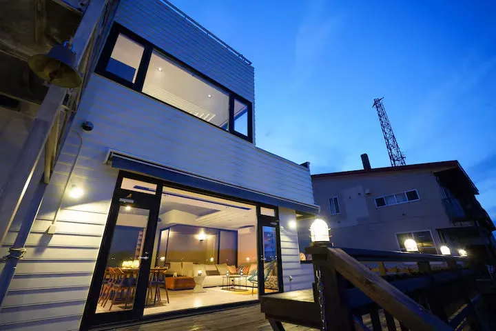 夜の家と青い空の画像。家の窓から見える部屋の様子も写っている。