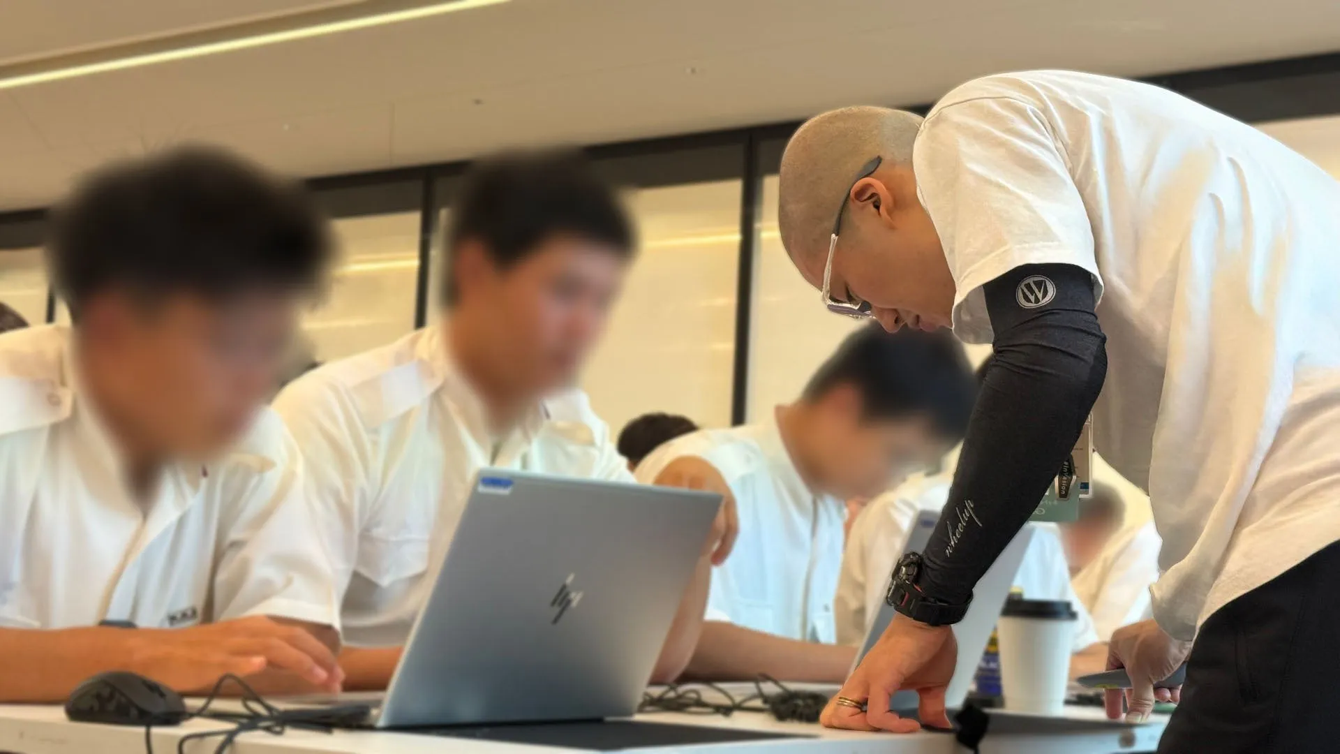 講師がパソコンで作業をする生徒たちを指導している様子