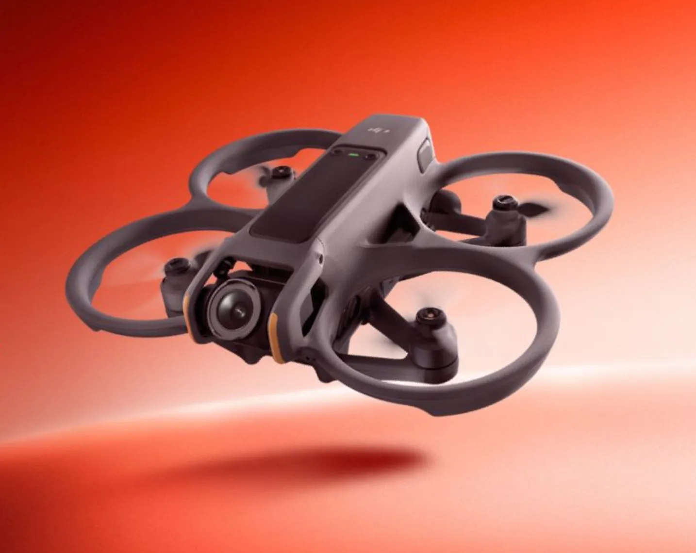 空中に浮かぶドローンのクローズアップ画像。オレンジ色の背景に、ドローンの黒いフレームとプロペラが際立っている。