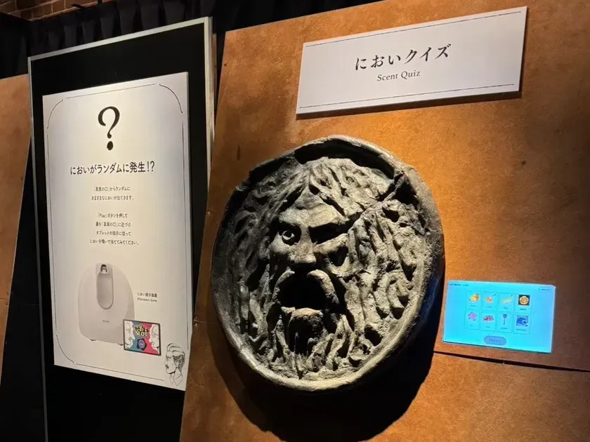 においクイズの展示。顔の彫刻とタブレットがあり、においを当てるゲームのようだ。