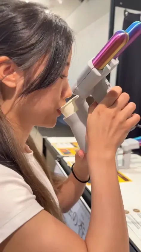 女性が、カップをくわえて、銃のようなものを持っている様子。