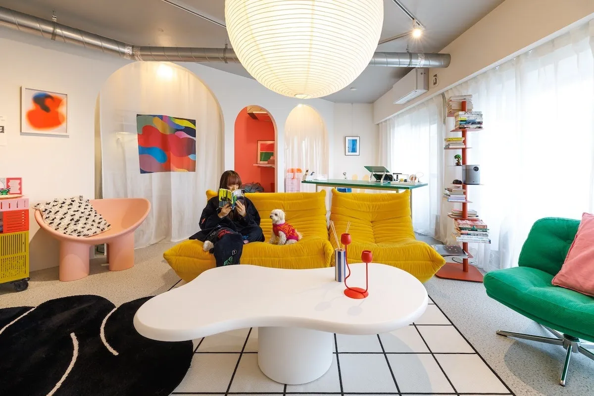 女性が黄色いソファで本を読み、犬が隣に座っている、モダンなリビングルームの画像