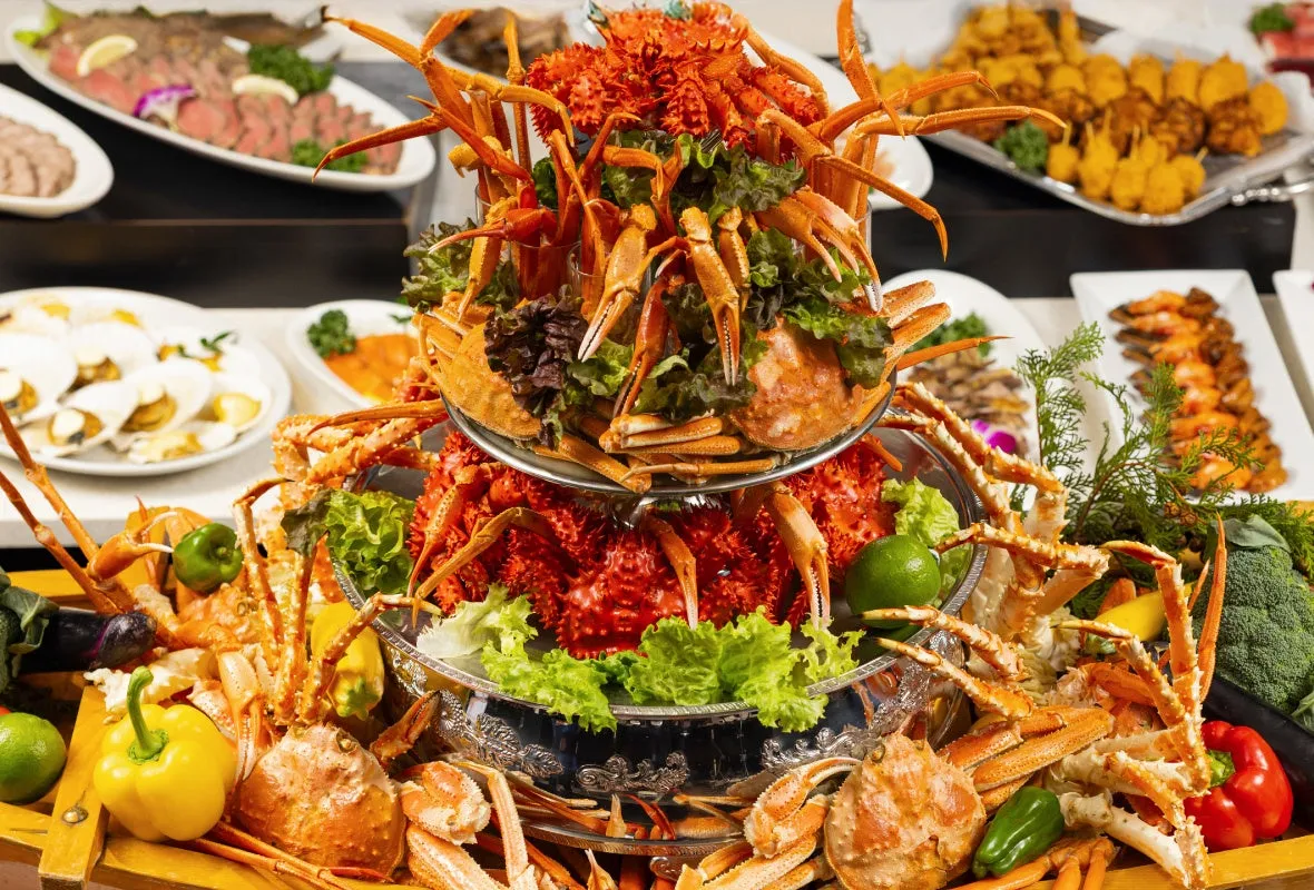 様々な料理が並んだビュッフェの光景。特に大きなカニの盛り合わせが目を引く。