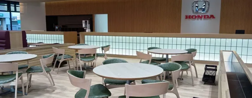 ホンダのショールーム内にあるカフェスペースの様子。丸テーブルと緑色の椅子が配置され、明るい雰囲気の空間が広がっている。