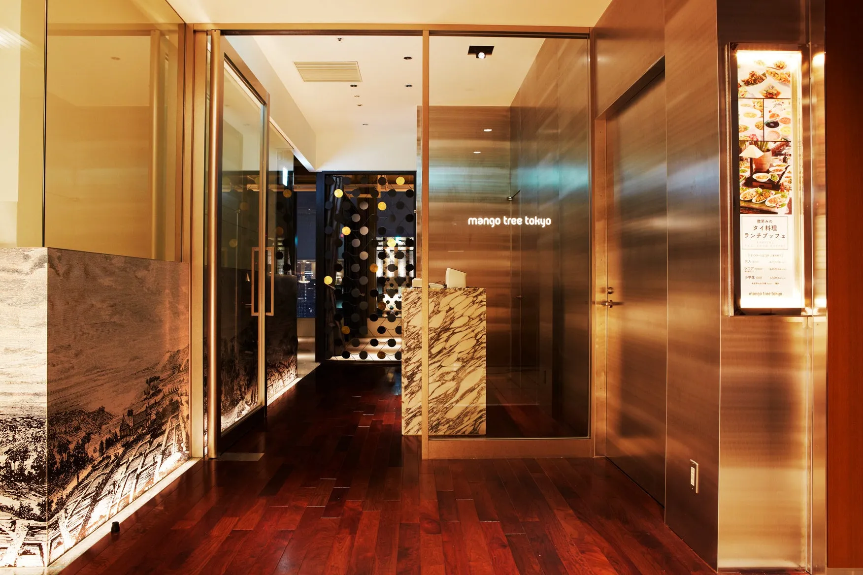 レストランの入り口。木製の床、大理石のカウンター、ガラス張りのドアが特徴的。