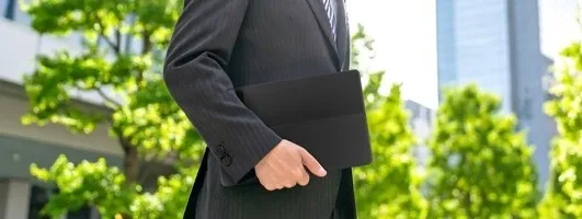 スーツを着た男性が黒いタブレットのようなものを持っている様子。