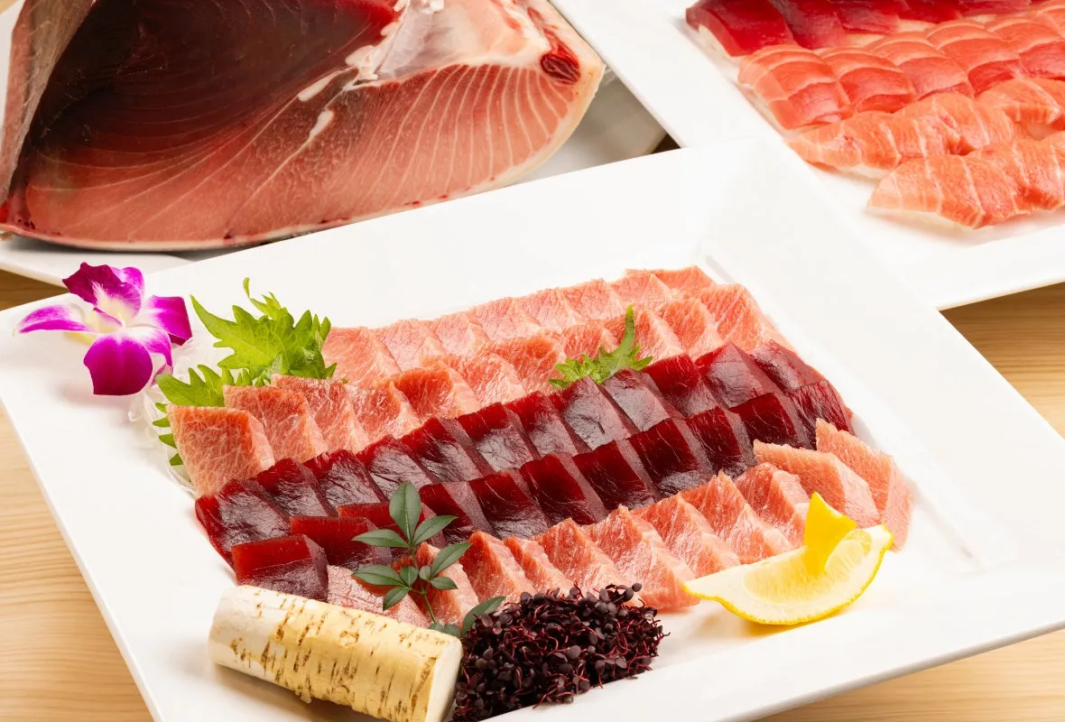 新鮮なマグロの刺身が美しく盛り付けられた写真。赤身とトロが交互に並べられ、薬味やレモンが添えられている。