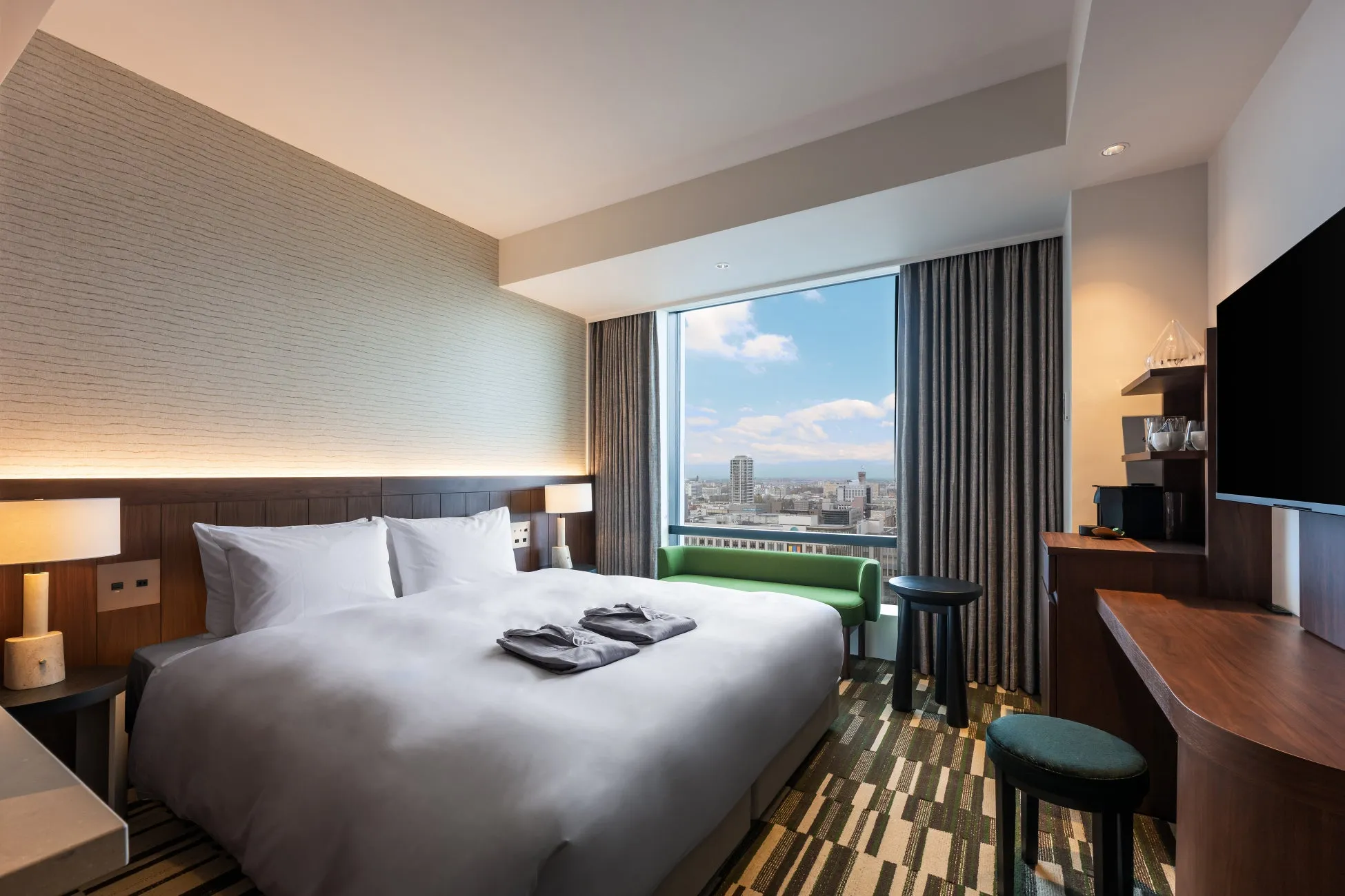 ホテルの客室。ベッド、窓、街並みが見える。
