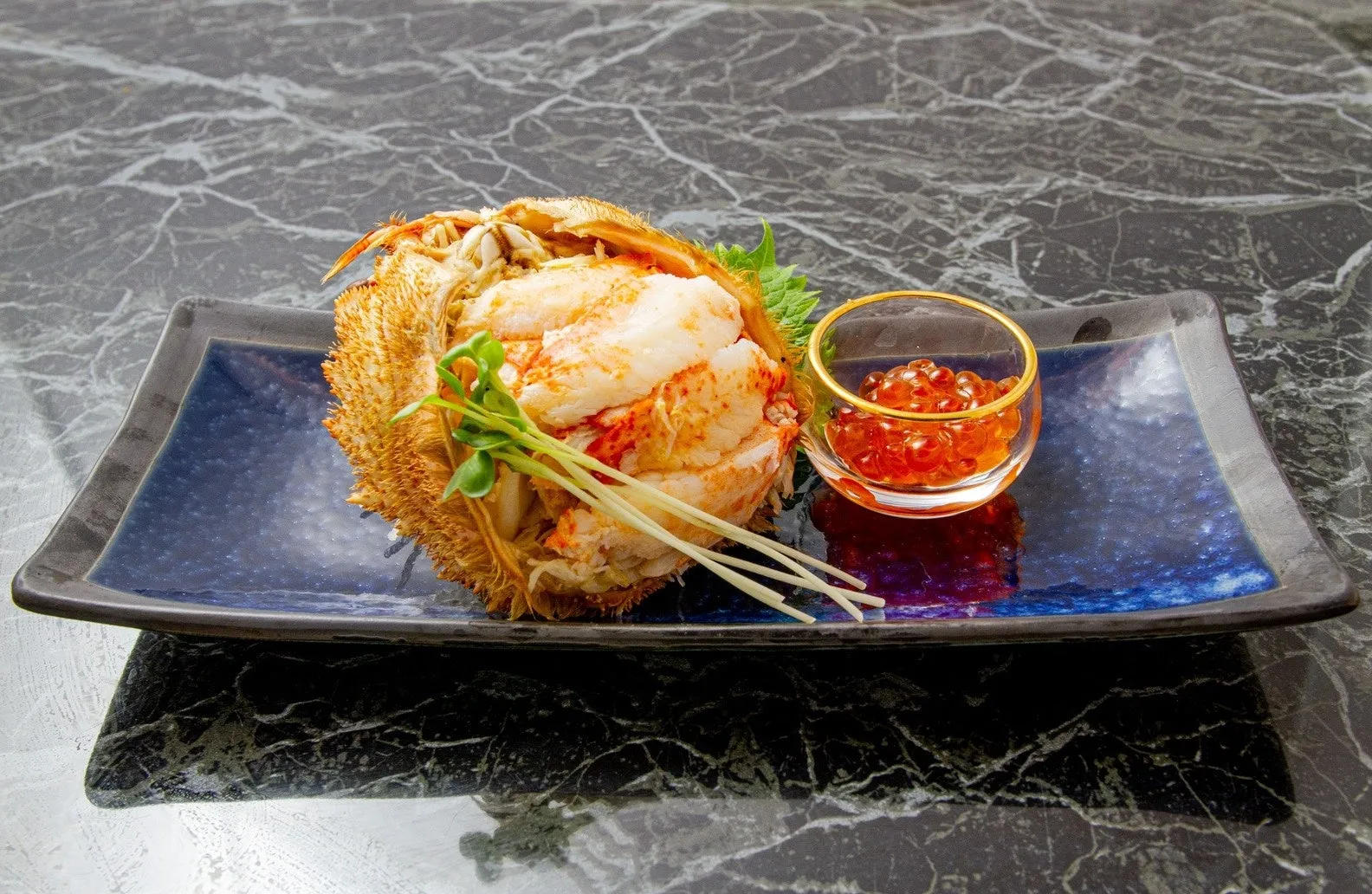 毛ガニの料理。毛ガニの身がむき出しになっており、いくらが添えられている。