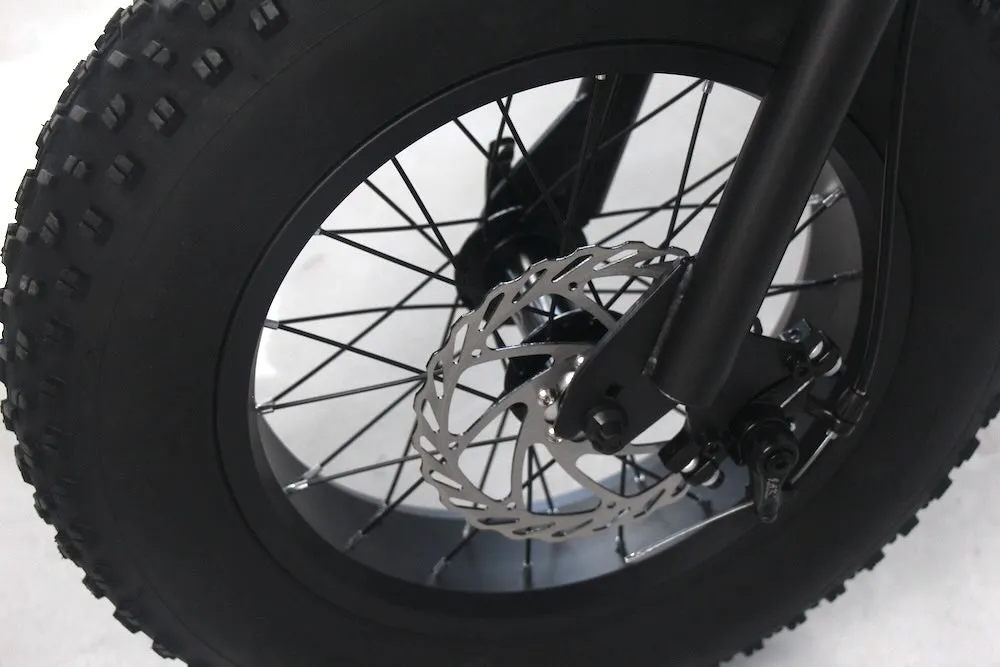 極太のオフロードタイヤとシルバーのディスクブレーキが特徴的な自転車のフロントホイールのクローズアップ画像です。