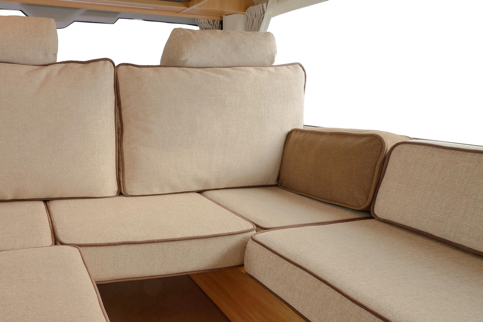 ベージュ色の布張りソファのクッションとヘッドレストが写っています。ブラウンのパイピングがアクセントになっており、清潔感のある快適な座席エリアを示しています。