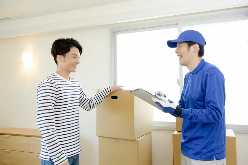 男性が引っ越し業者から荷物を受け取っている様子。