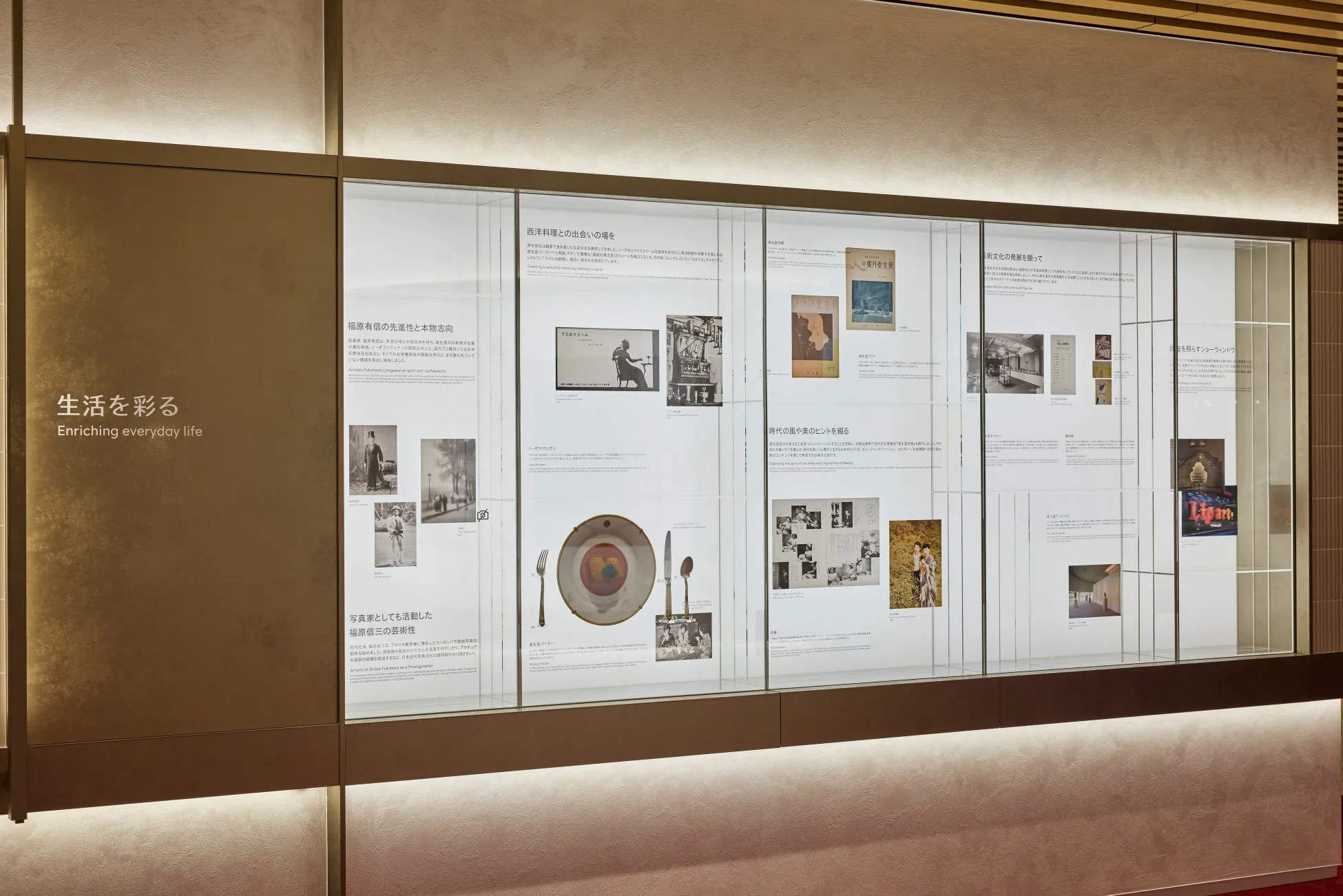 展示会の様子を写した写真。壁には、福原有信、写真家としての福原信三、西洋料理との出会い、芸術文化の発展、時代の風、美のヒントなど、さまざまなテーマに関する展示パネルが並んでいます。