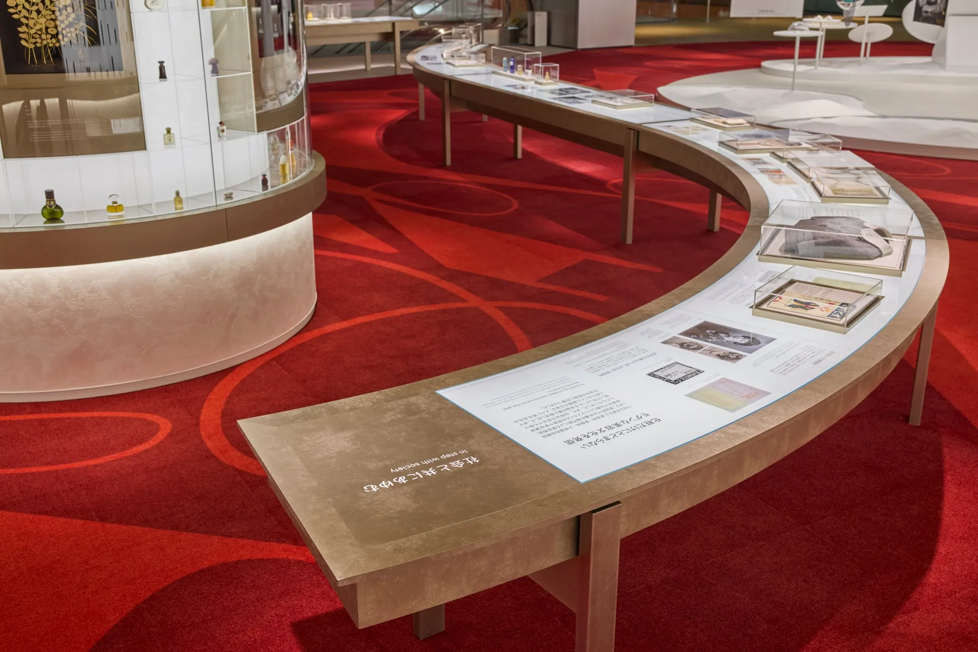 展示会の様子。曲線の展示台に、写真や資料が展示されている。