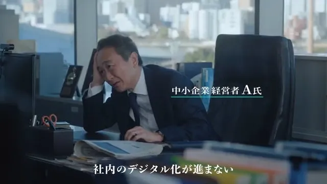 オフィスで頭を抱える中小企業の経営者。デジタル化が進まないことに悩んでいる様子。