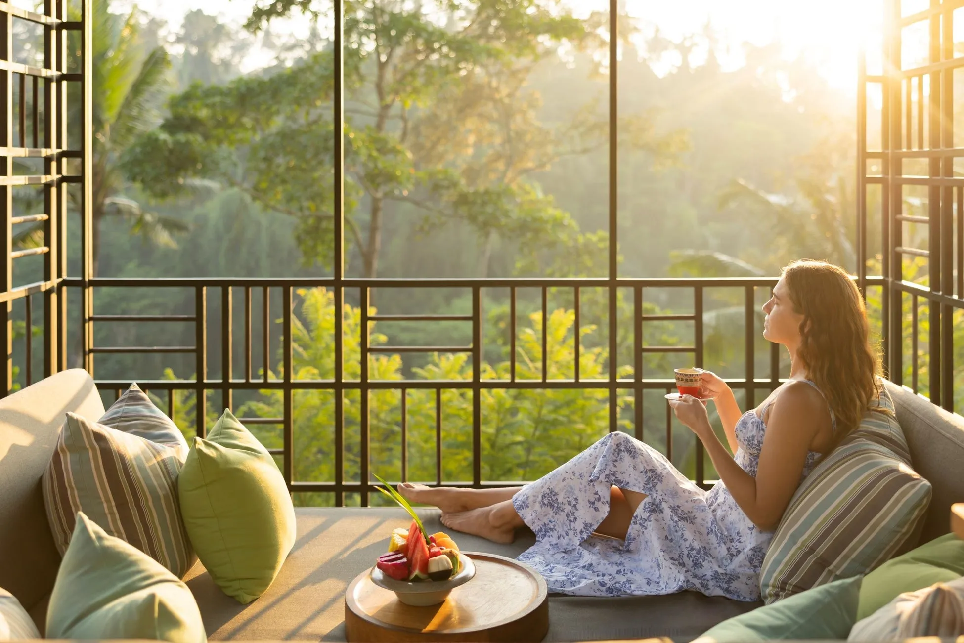 女性が屋外のソファに座り、飲み物を楽しんでいます