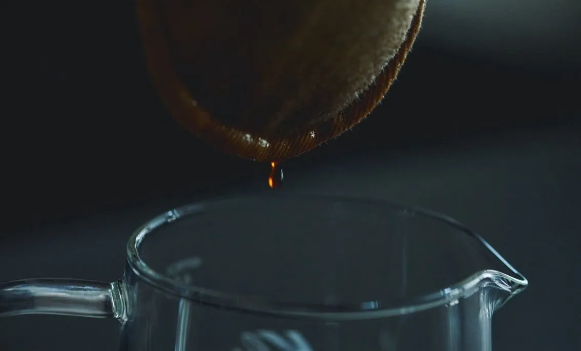 コーヒーを抽出している様子。コーヒーフィルターからコーヒーが滴り、ガラスのピッチャーに落ちている。