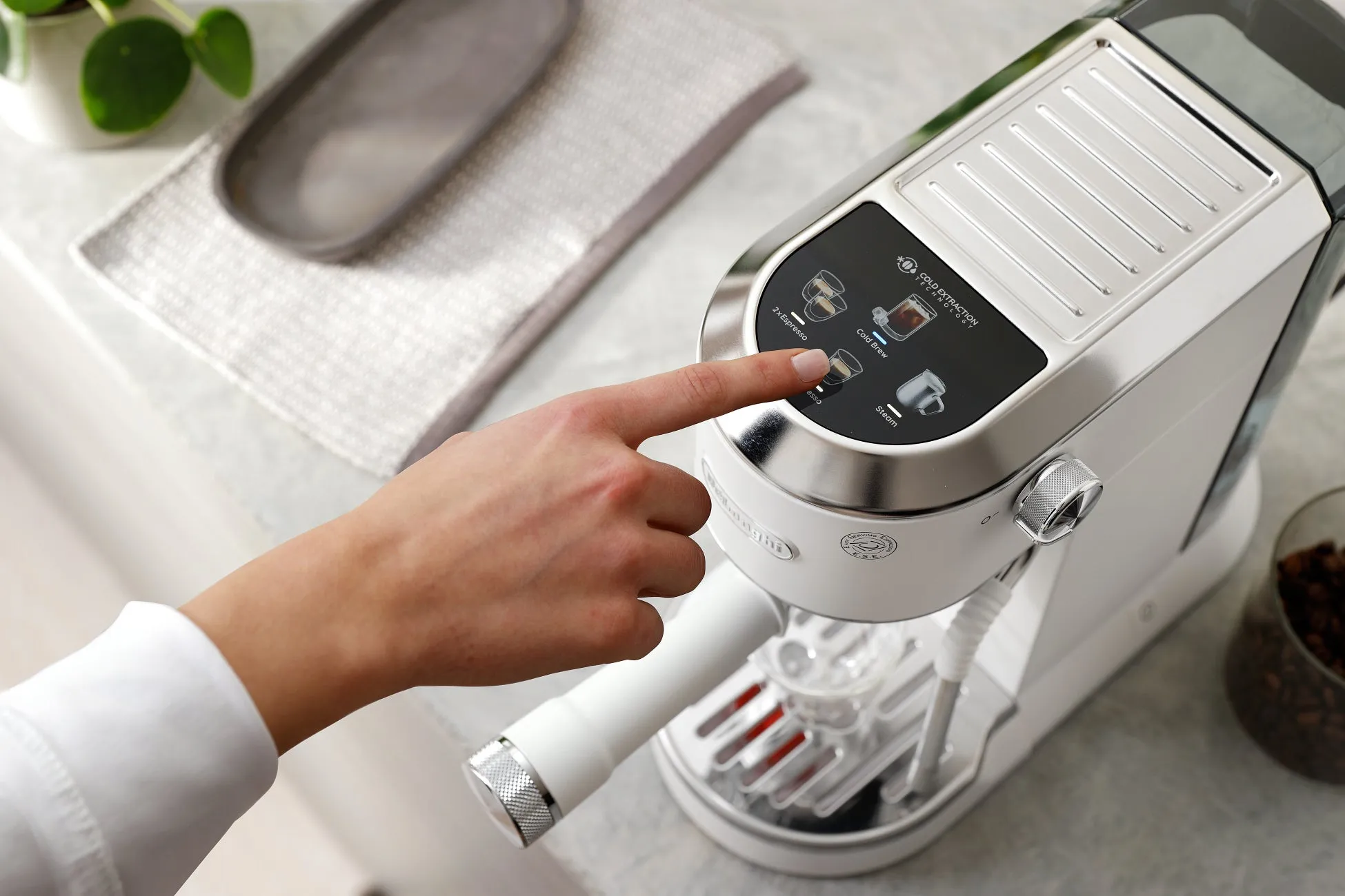白いエスプレッソマシンに手を置いている様子