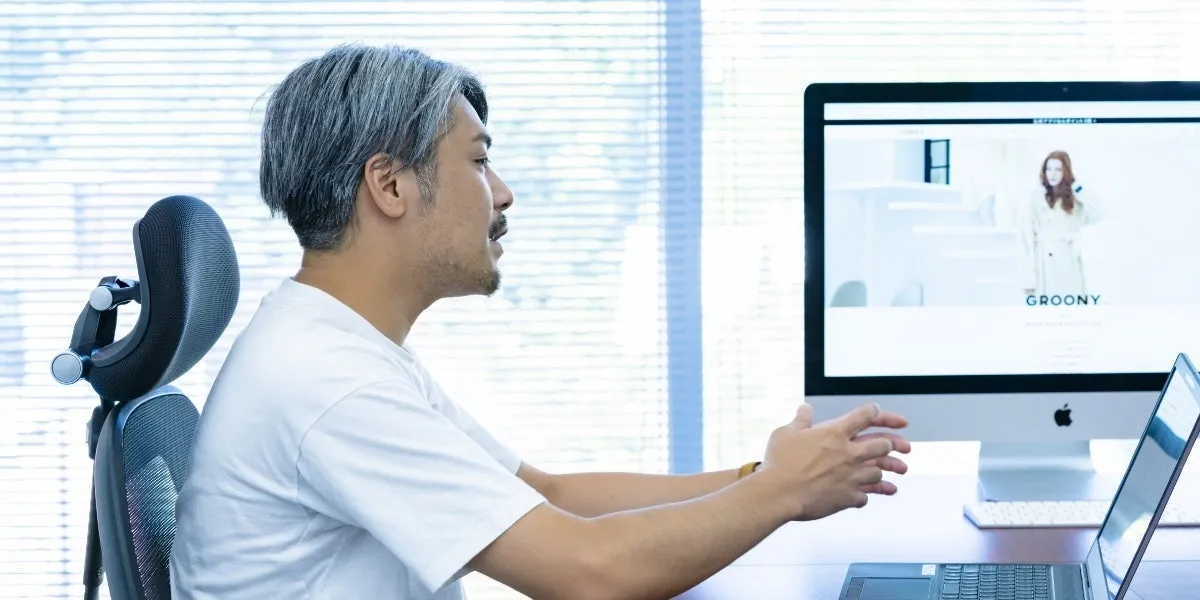 男性がオフィスでパソコンに向かって話をしている様子を捉えた写真