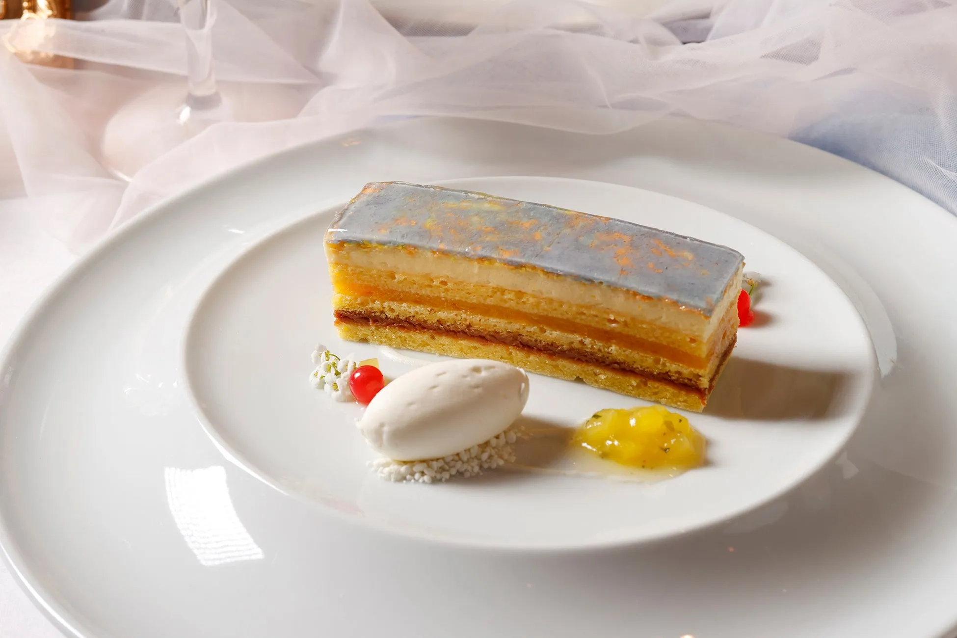 白い皿の上に、長方形のケーキとアイスクリーム、ソースが添えられたおしゃれなデザートのクローズアップ写真。