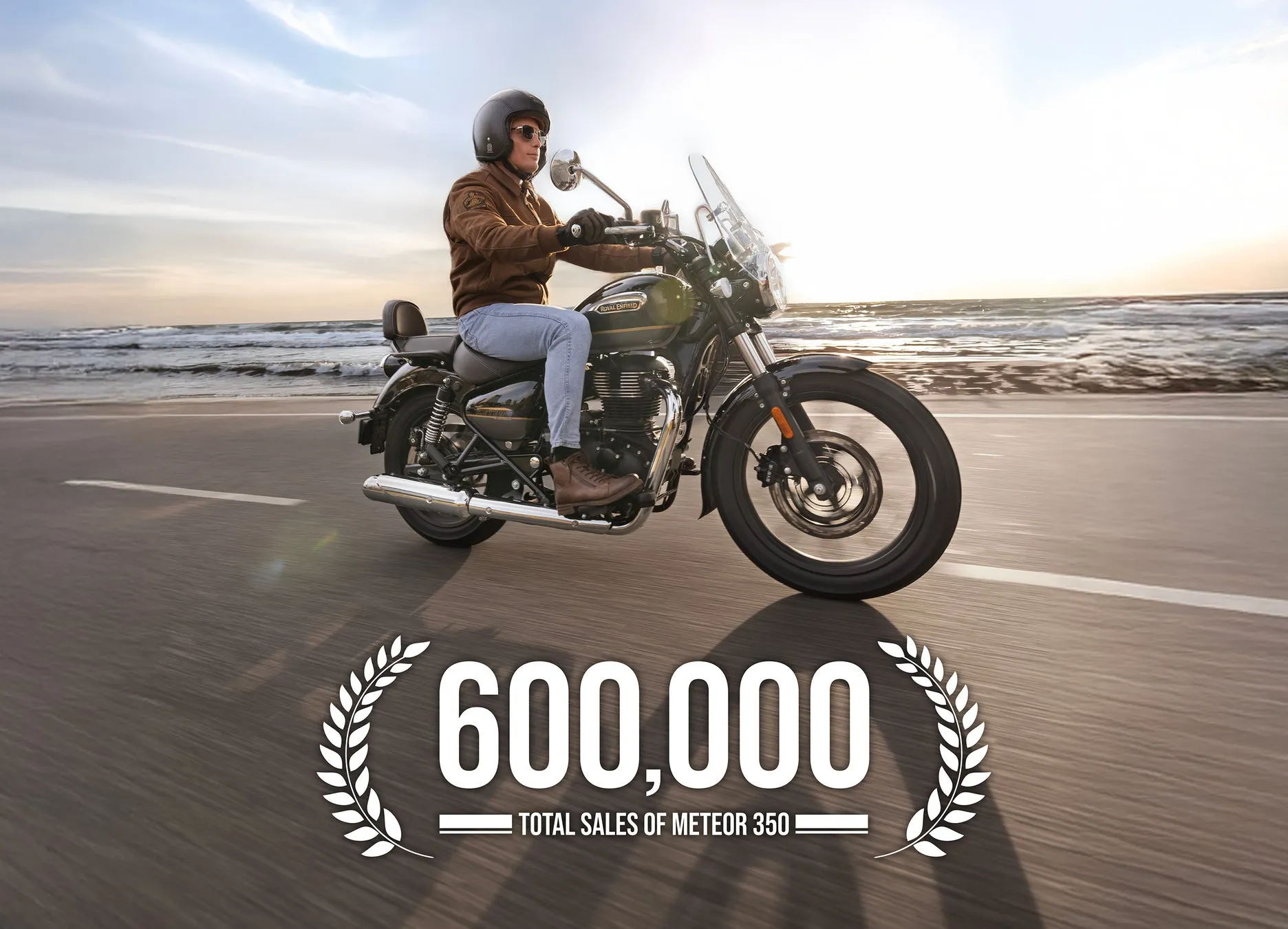 バイクに乗った男性が、海沿いの道路を走っている様子。60万台突破の文字。