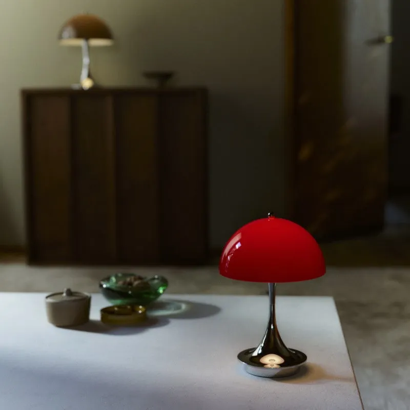 白いテーブルの上に赤いランプが置かれ、その奥には茶色のランプと木製キャビネットが見える