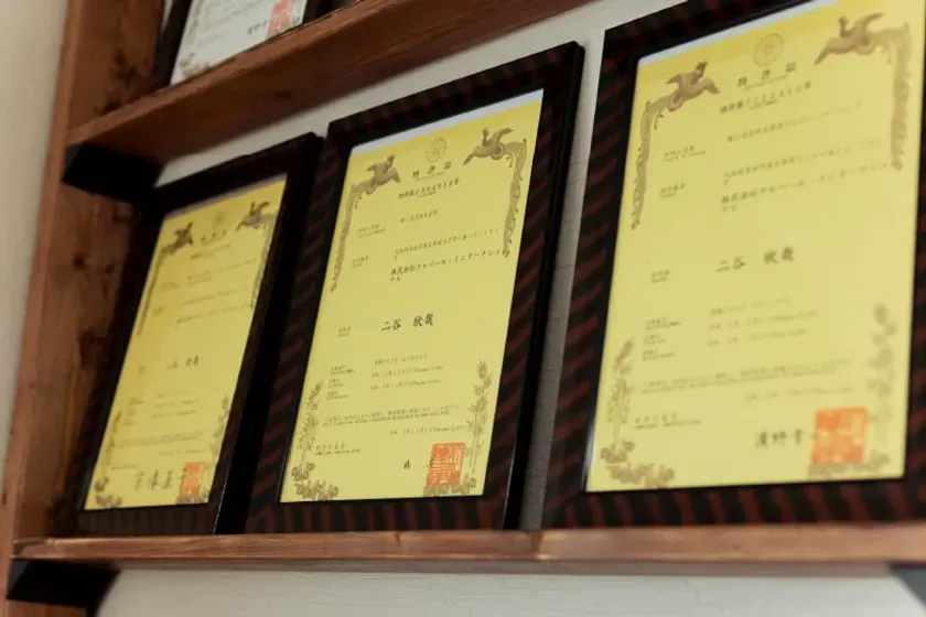 額縁に入った3つの証明書が木製の棚に飾られています。