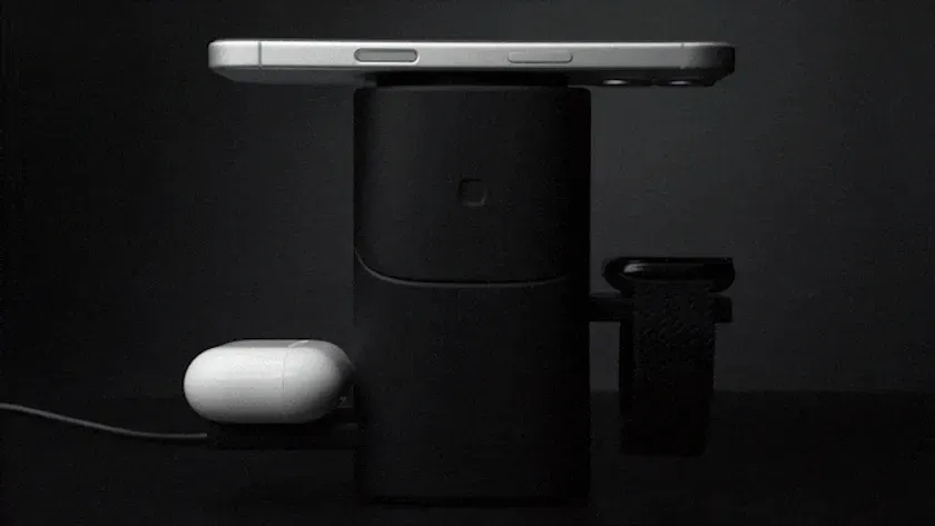 黒い充電器の上にスマートフォン、イヤホン、スマートウォッチが置かれている写真です。