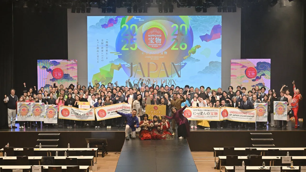 イベントの様子。多くの人々がステージ上でロゴを背景にポーズをとっている。