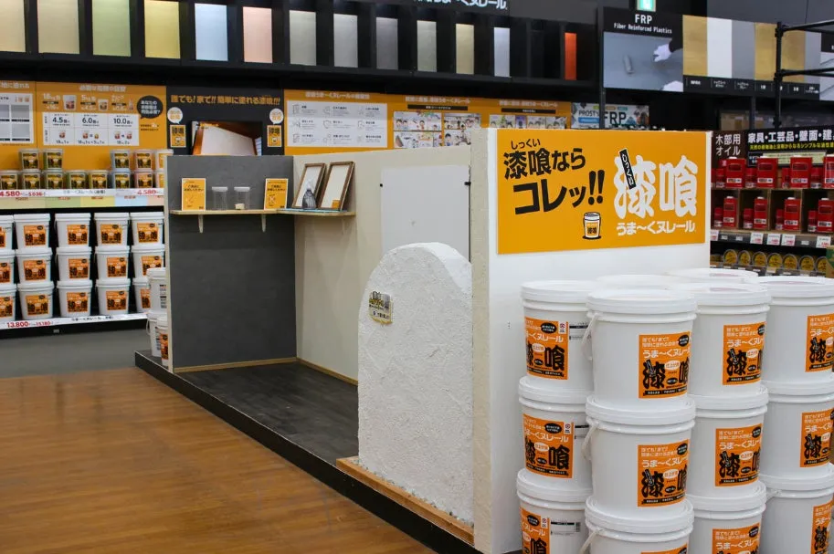 店舗のディスプレイ。漆喰関連の商品が並べられ、塗り方の見本や商品情報が表示されている。