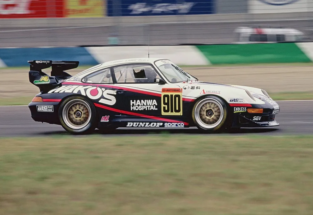 レース中のポルシェ911のレーシングカー。車体にはスポンサーのロゴやナンバーが描かれている。