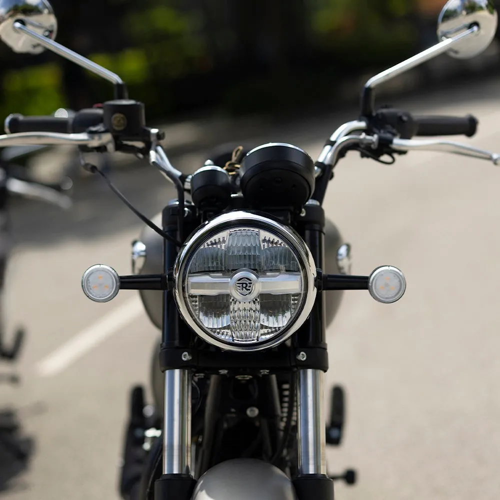 バイクの正面のクローズアップ。丸いヘッドライト、バックミラー、ハンドルバーが見える。