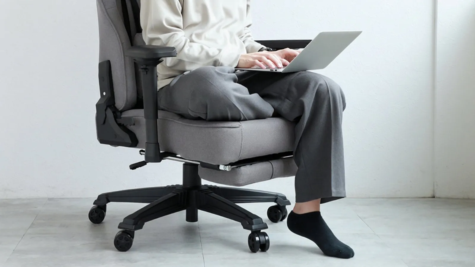 椅子に座ってノートパソコンを操作している人の写真です。