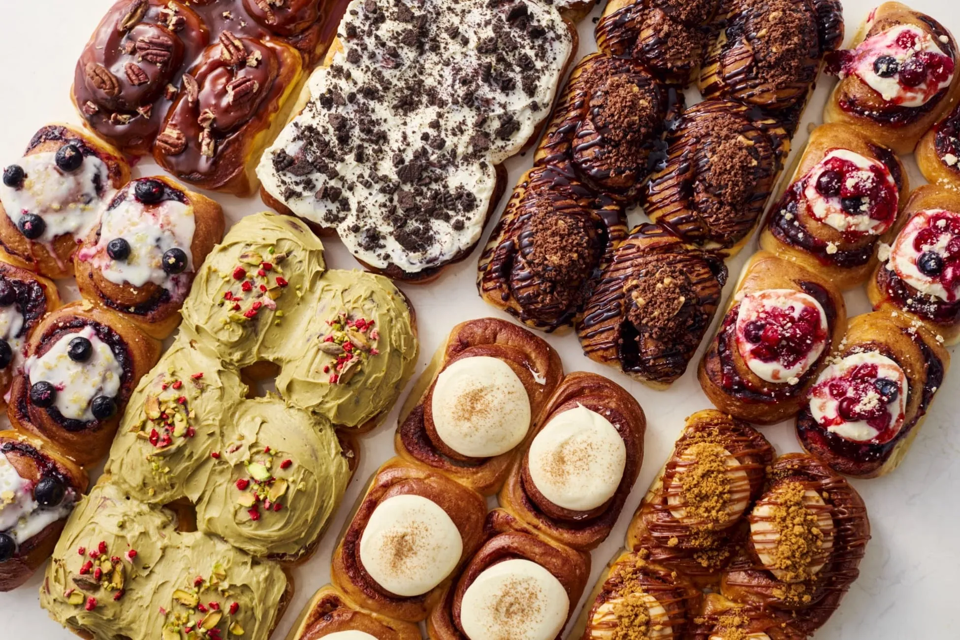 様々な種類のデニッシュパンが並べられた写真。チョコレート、クッキー、ベリー、ピスタチオ、シナモンなど、様々なトッピングが施されている。