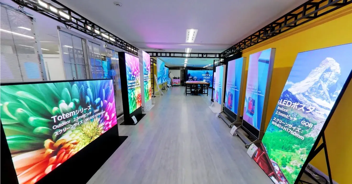 LEDディスプレイ製品が多数展示されたショールームの様子です。壁沿いに様々なサイズの高精細LEDスクリーンが並び、「Totemシリーズ」や「LEDポスター」といった製品名と仕様が示されています。鮮やかな映像コンテンツが映し出され、奥には「XRビジョン」の表示も見えます。