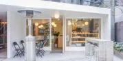 カフェの外観。白を基調としたシンプルなデザインで、屋外席や大きな窓が特徴的。