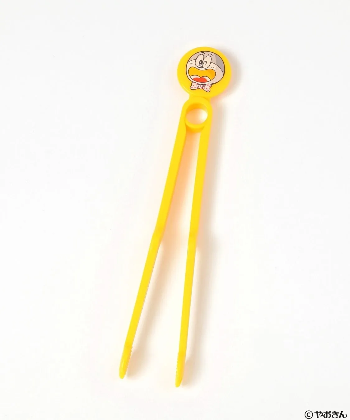黄色いお菓子用のトング。先端にキャラクターの顔が描かれている。
