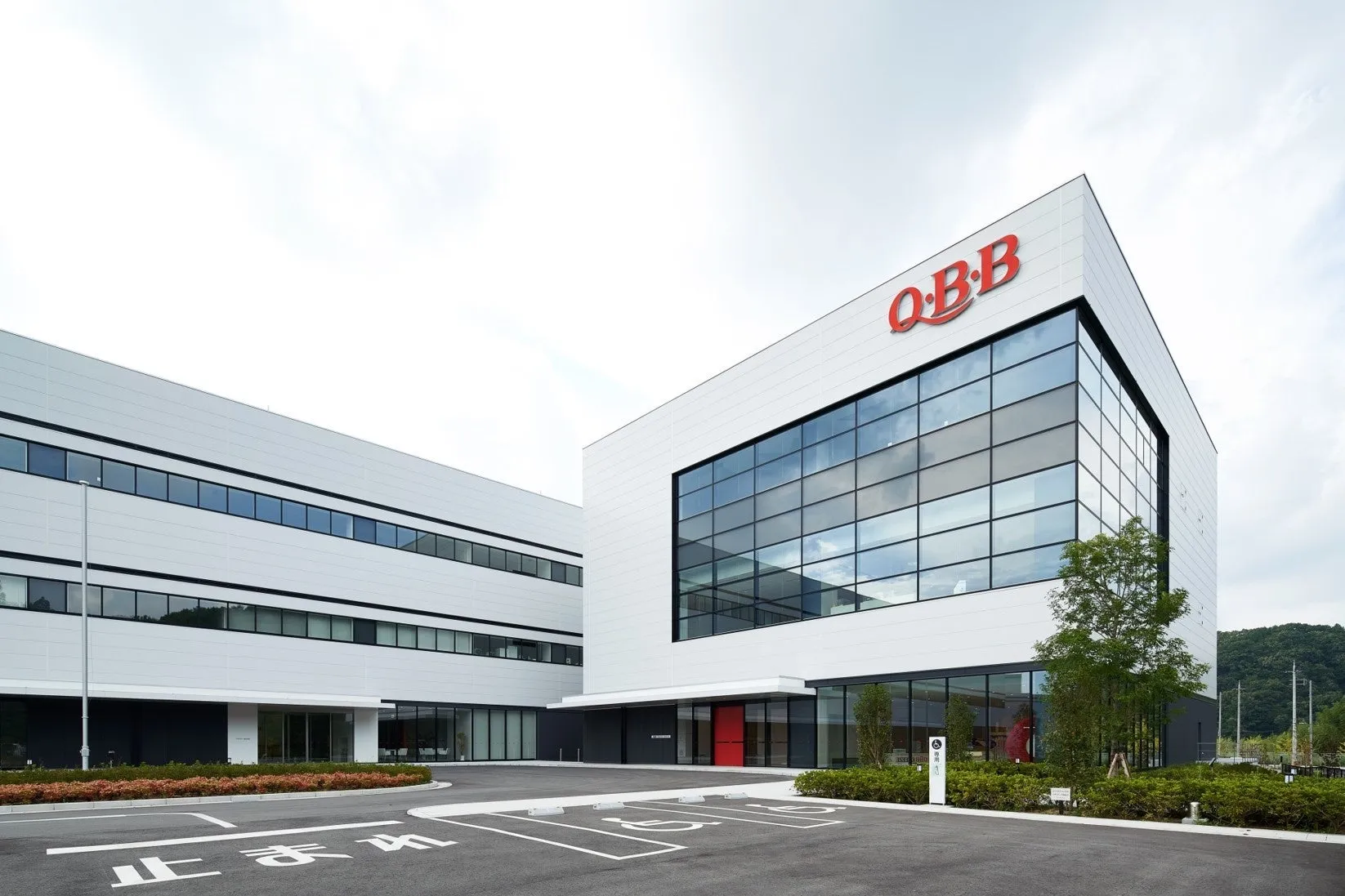 白い建物で、O・B・Bのロゴがあります。駐車場には、止まれの標識と障害者用の駐車スペースがあります。